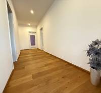 A hallway in a 4-room apartment with light walls and wooden flooring.