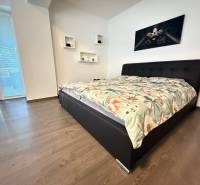 Bedroom with a bed and a painting in a 4-room apartment, wooden floor, large window.