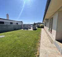 A family house in Prešov with a lawn and a paved walkway in a sunny yard.