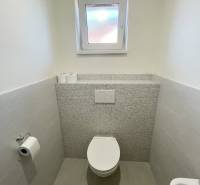 Bathroom in a family house with ceramic tiles and a toilet.