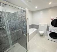 A bathroom in a family house with a bathtub, shower, and a washer with a dryer.