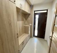 Entrance hall with wooden furniture in a family house, includes storage space and entrance doors.