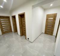 A hallway in a family house with wooden doors and glossy tiles.