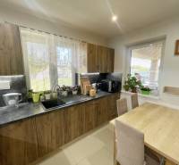A kitchen in a family house with wooden cabinets and a dining table.