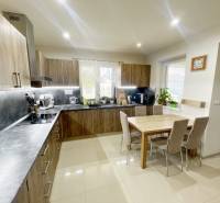 A kitchen in a family house with built-in appliances and a dining table for six people.