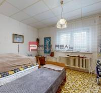 Room with a bed, carpet, and walker in a family house.