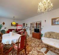 Living room in a family house with furniture, carpet, chandelier, curtains, and paintings.