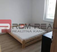 Simple bedroom with light, bed, and furniture in a two-room apartment on Slavomírova Street.