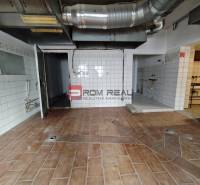 Commercial premises with tiles and cladding, containing ventilation ductwork and a door to the back area.
