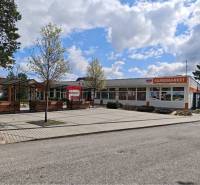 Commercial premises on Partizanska Street in Svätý Jur with a supermarket, benches, and trees.