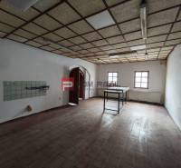 An empty interior of commercial premises with a tiled wall and skylights.