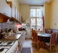 A kitchen with a dining table in a 2-room apartment, light walls, and wooden cabinets.