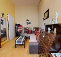 Living room in a two-room apartment with wooden furniture, a sofa, and a television.