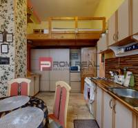 A kitchen with a dining table and a gallery in a 2-room apartment, wooden and brick decor.