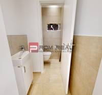 Interior of commercial premises with a toilet, sink, and tiles, suitable for rent.