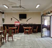 Interior of a gastro space with tables and chairs, decorations on the walls, and a TV.