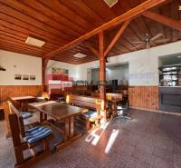 A wooden interior of a family house with benches and tables, light coming through the window.