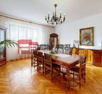 Dining room in a family house with wooden furniture, a painting, and parquet flooring.