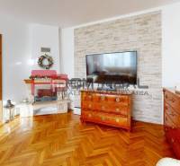Living room with wooden flooring, a fireplace, and a large television in a family house.