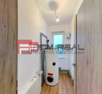 A narrow space with a boiler and white walls in a family house.