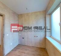 A space in a family house with tiles and a large window, ready to be furnished.