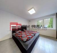 A bedroom in a family house with a double bed, dark furniture, and large windows.