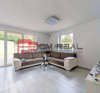 Living room in a family house with a sofa, windows, and a television.