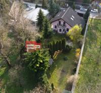 A family house in Píla surrounded by trees with a landscaped garden and neighboring buildings.