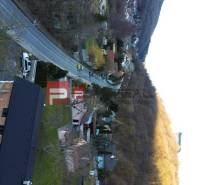 Family houses in the village of Píla, lined with a road and forest.