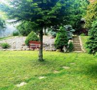 A garden at a family house in Píla with a lawn, trees, and stone steps.