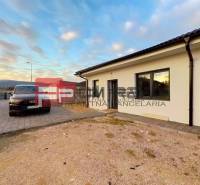 A family house in Častá with a car on a paved courtyard, sky with soft clouds.