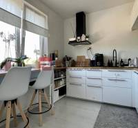 A kitchen in a 3-room apartment with white cabinets and bar stools.