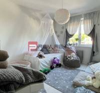 A children's room in a 3-room apartment with toys and a bed, with a view through the curtains.