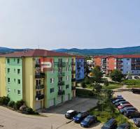 Colorful apartment buildings on Muškátová Street in Pezinok with cars in the parking zone.