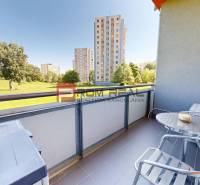 The balcony of a 1-room apartment on Koprivnicka 9/F in Bratislava IV with a view of greenery and panel buildings.