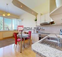 The kitchen and living area in a studio apartment with a light-colored furnished kitchen unit.