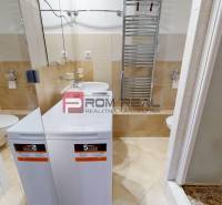 Bathroom with a washing machine, sink, and shower in a studio apartment, bright tiles.