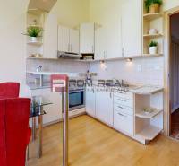 A kitchen in a studio apartment with a dining table and built-in appliances.