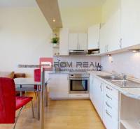 A kitchen with a dining table and red chairs in a studio apartment.