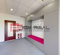 Interior of an office with a coat rack wall, a pink bench, and fire safety equipment.