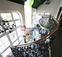 The interior features an elegant staircase and a balcony on Ľ. Podjavorinská Street, with oversized windows highlighting the historic building.