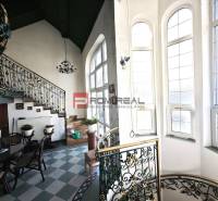 Interior of a building with a decorative staircase on Ľ. Podjavorinská Street, large windows letting in light.