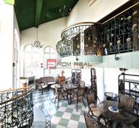 Interior of the building on Ľ. Podjavorinská Street with decorative railing, wrought iron chairs, and table.