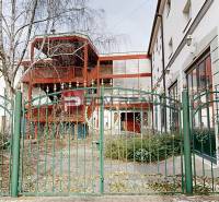 The garden in front of the building on Ľ. Podjavorinská Street in Trnava, with a green metal fence.