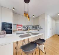 A kitchen in a 2-room apartment with a white counter and chairs.