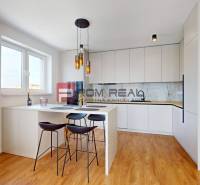 A kitchen in a 2-room apartment with a bar counter, stools, and built-in appliances.