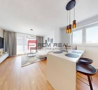 A bright living room with a kitchen, TV on the wall, wooden floor, bar seating. 2-room apartment.