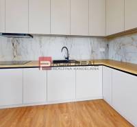 A kitchen in a 2-room apartment with light cabinets and wooden flooring.