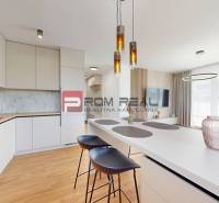 Kitchen and living room with an island and chairs in a two-room apartment.