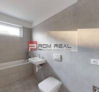 A bathroom in a 2-room apartment with a bathtub and a sink in a neutral color scheme.